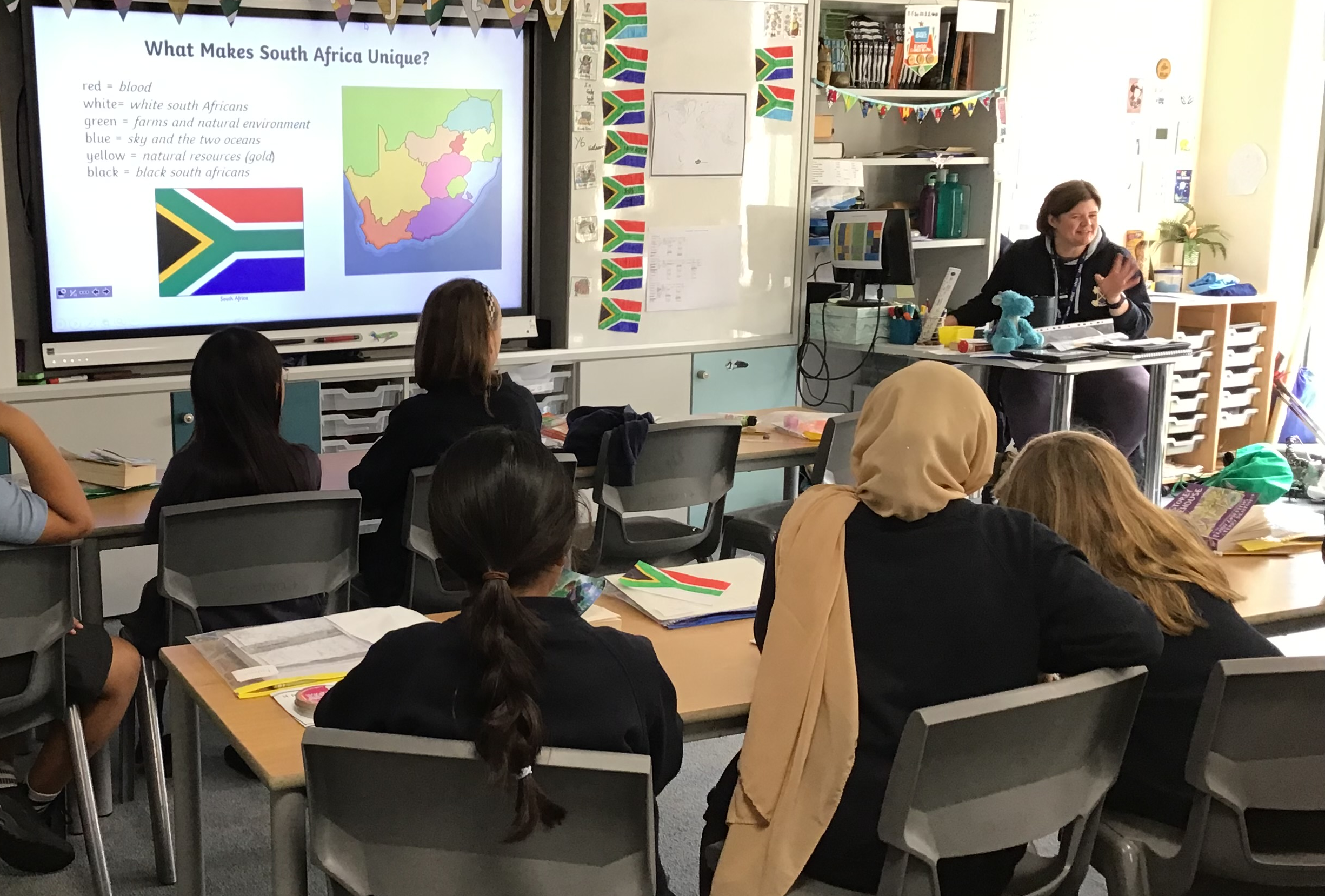 Six children, facing away from the camera, learning about South Africa